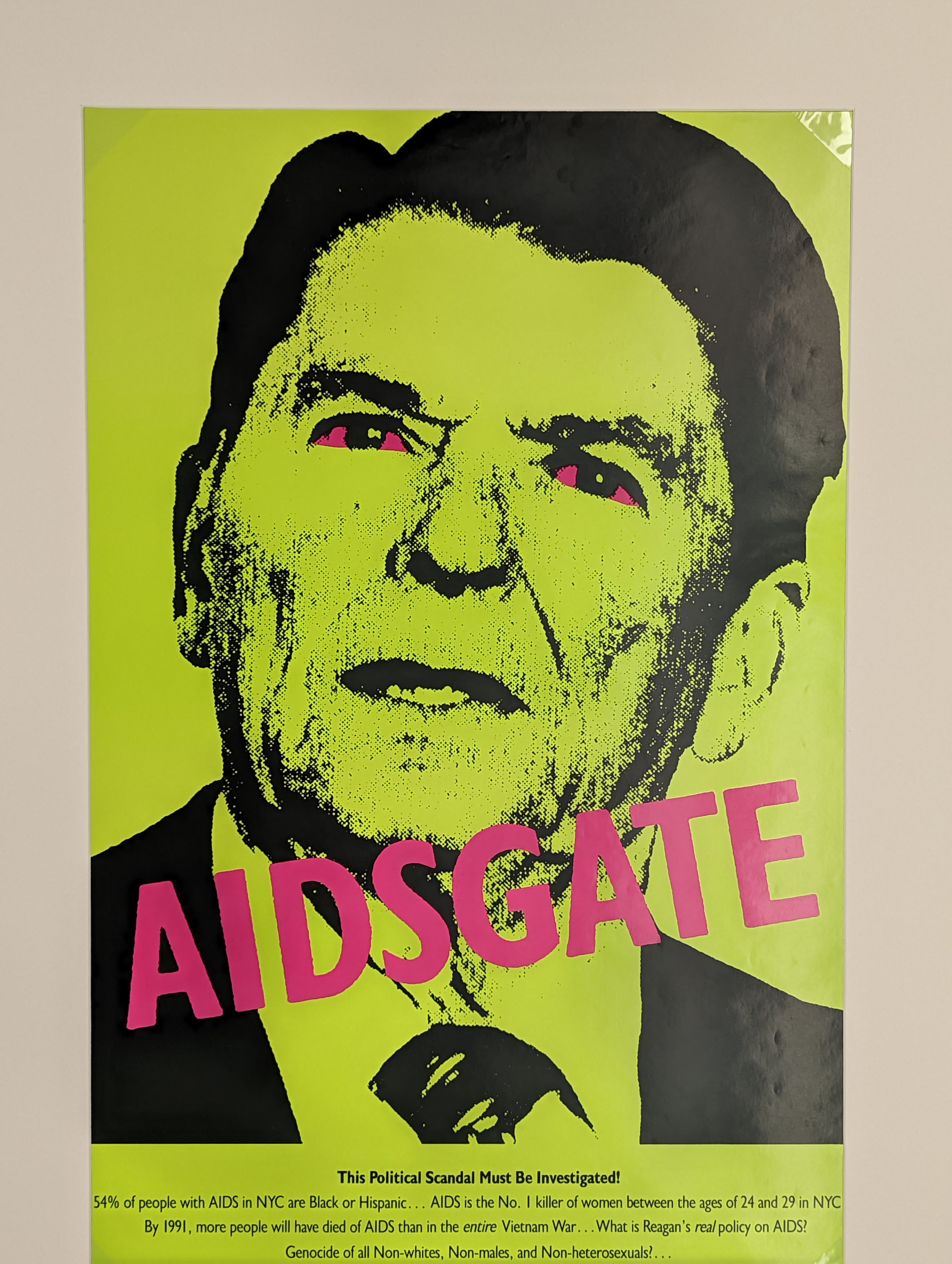 Screen print style picture of Ronald Reagan with pink eyes and the words &quot;AIDSGATE&quot; written over his face&quot;