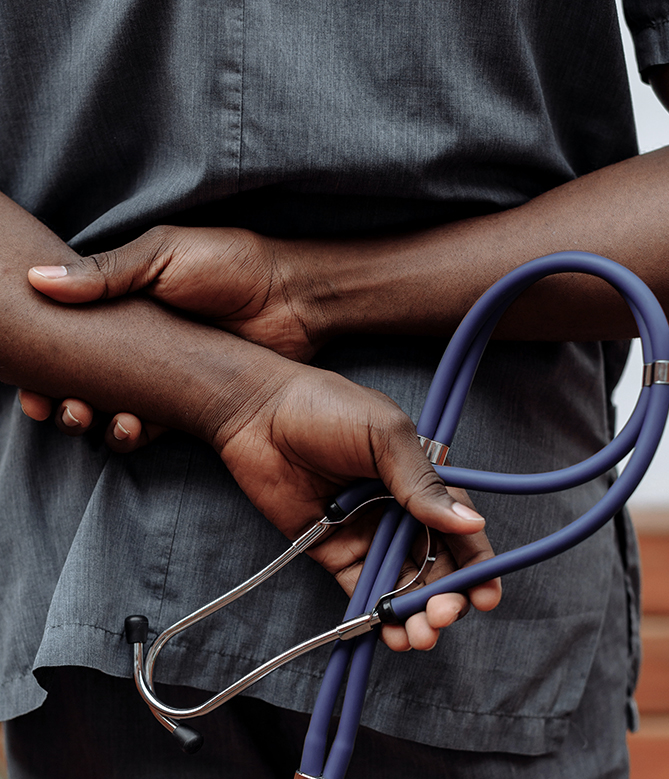 a black person wearing scrubs and holding a stethoscope behind their back
