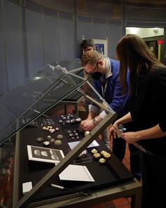 three people installing the exhibition items in glasses cases in the medical library rotunda