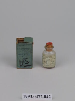 A small bottle of opium tincture next to its box. 