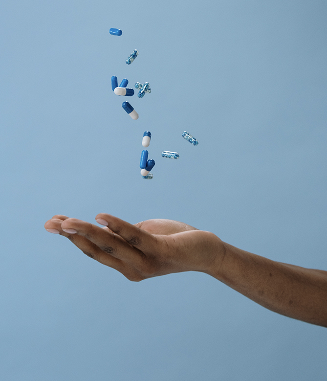 pills dropping into someone's hand, presented on a blue background