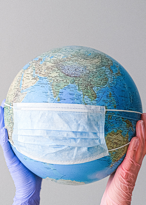 a globe with a mask on held by two hands